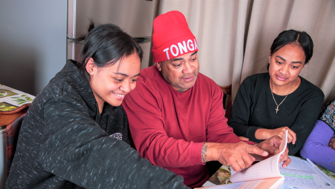 A father and his two daughters look at NCEA coursework