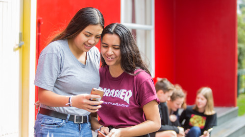 Two students smile at phone