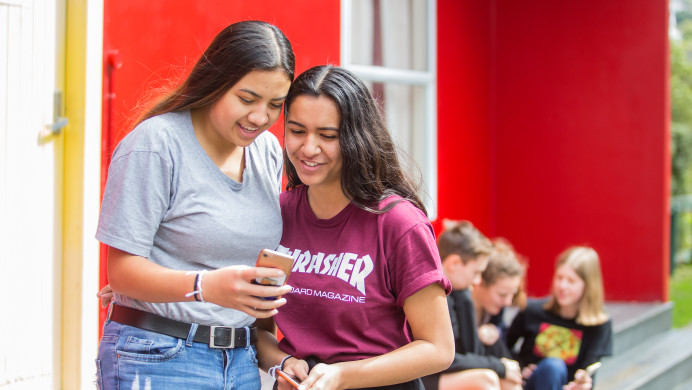 Two students smile at phone
