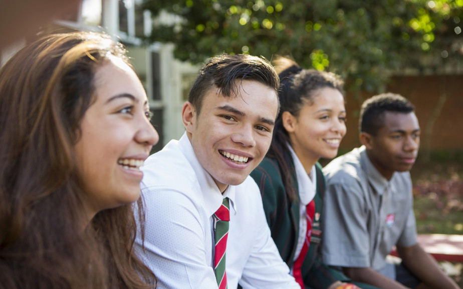 Student smiles at camera. He is with a group of friends.