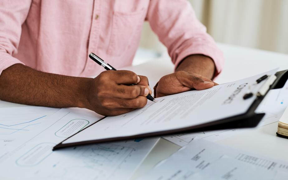 A man's hands are holding a clipboard and a pen