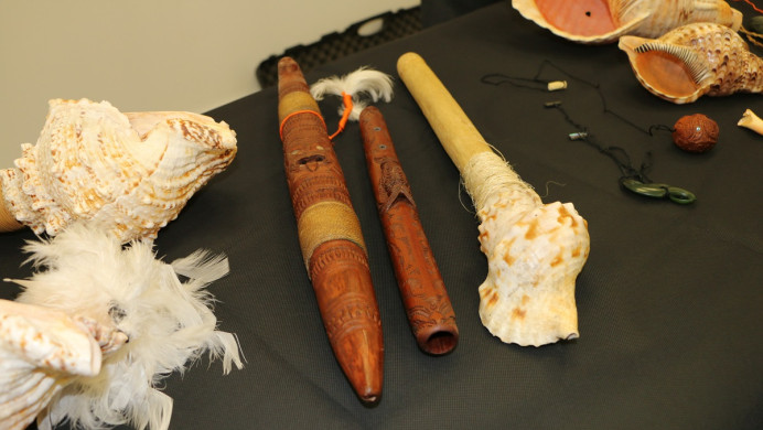 A collection of taonga puoro. Three shell and feather taonga puoro, or nose flutes, and two made of wood.