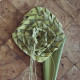 Green woven flower made of flax on wood