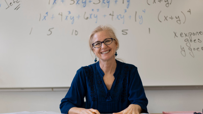 A teacher sits at her desk and smiles