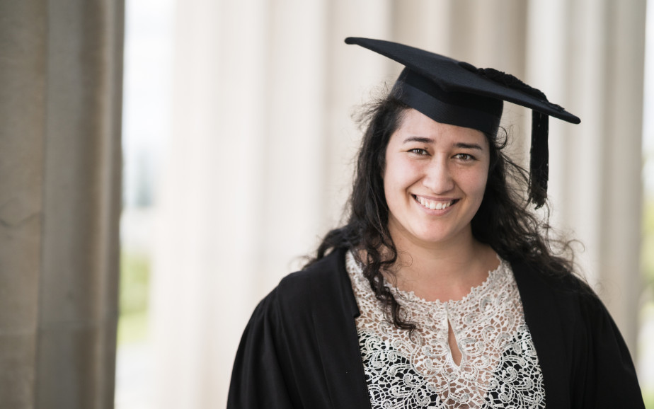 A smiling graduate is dressed in a gown