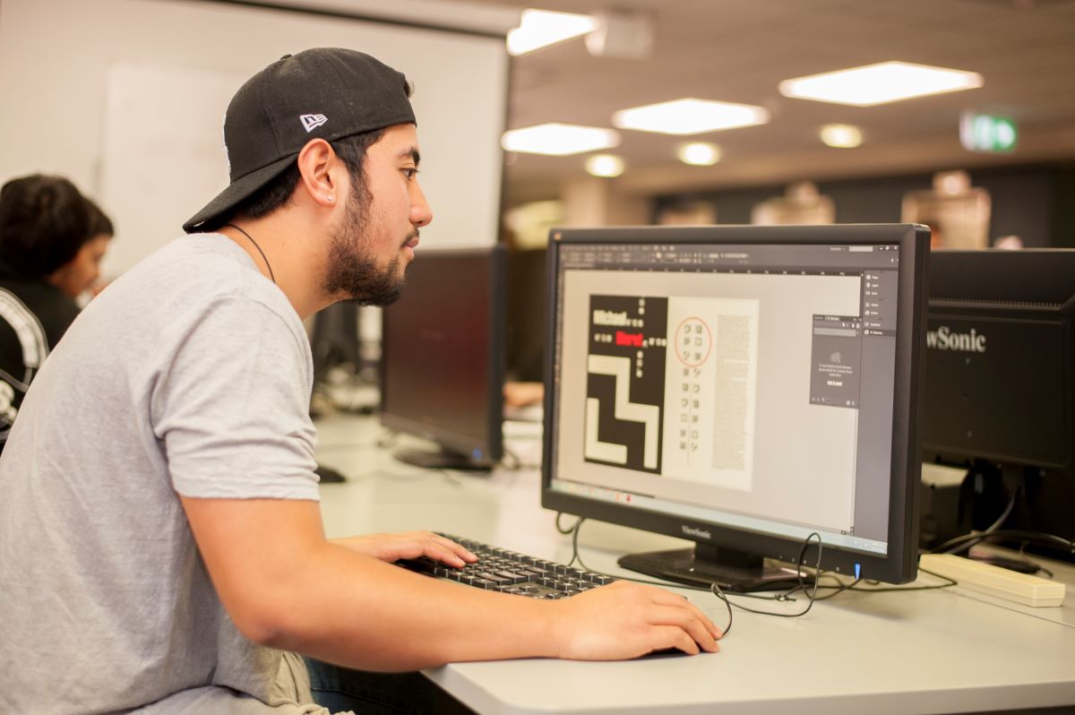 A young intern sits at a computer in an office.