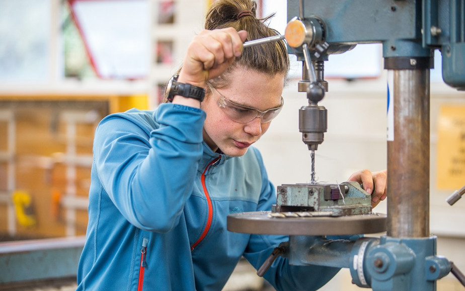 Young person drilling into metal