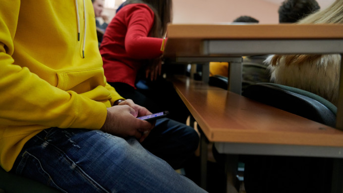 A student uses their phone under a desk during an assessment