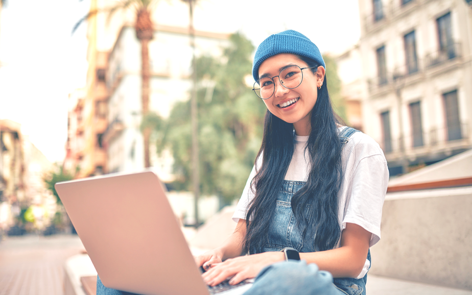 Student on laptop smiles at camera